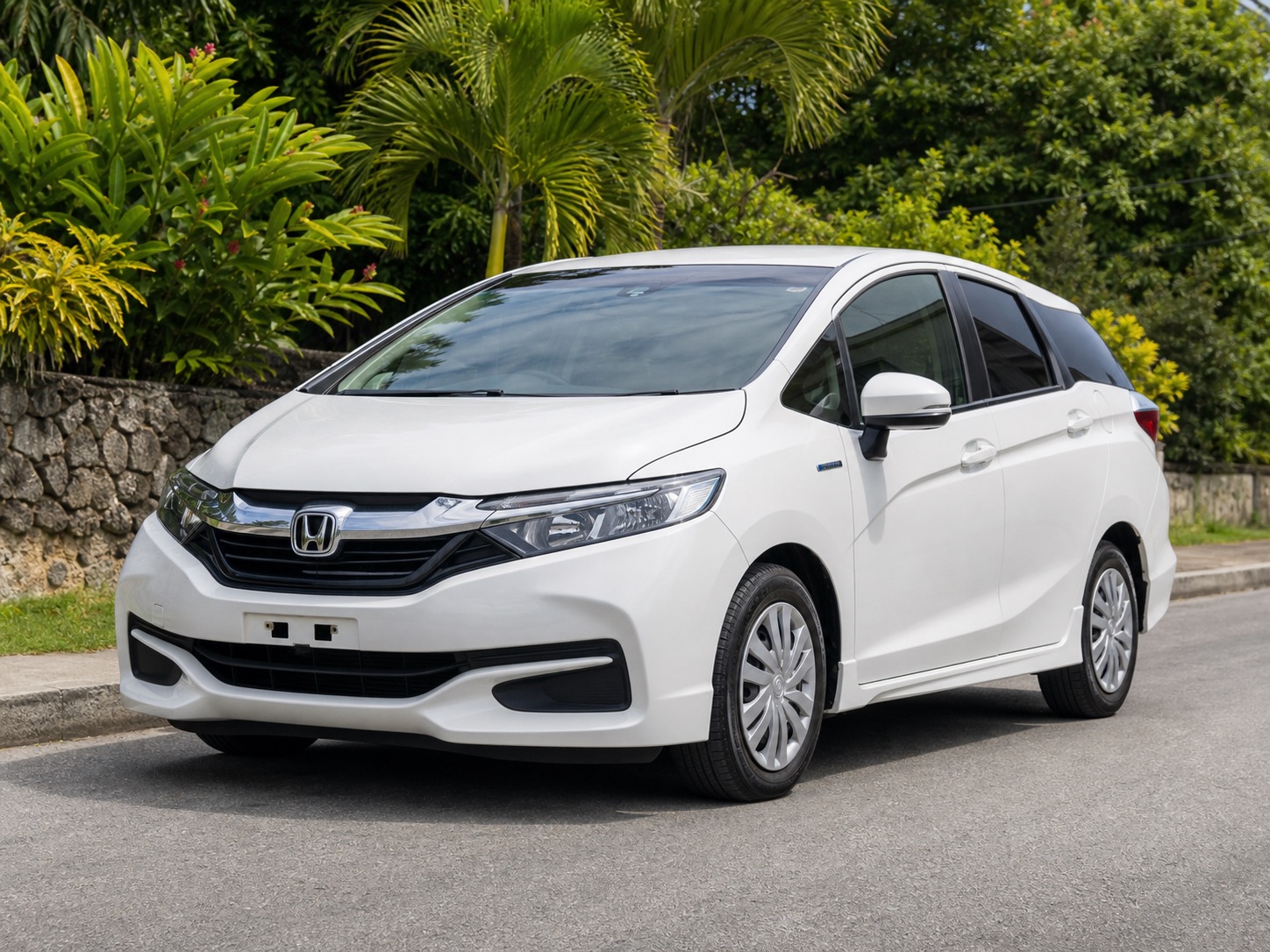 White 2018 Honda Shuttle parked on a Jamaica road with tropical greenery
